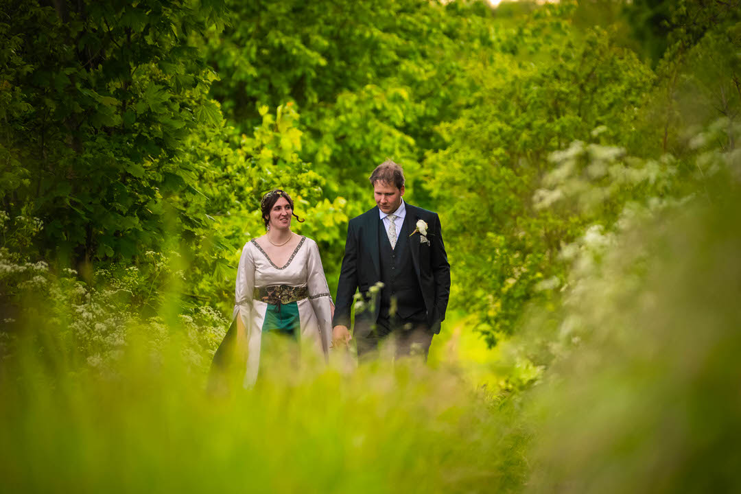 Bride and groom walking through lush woodland