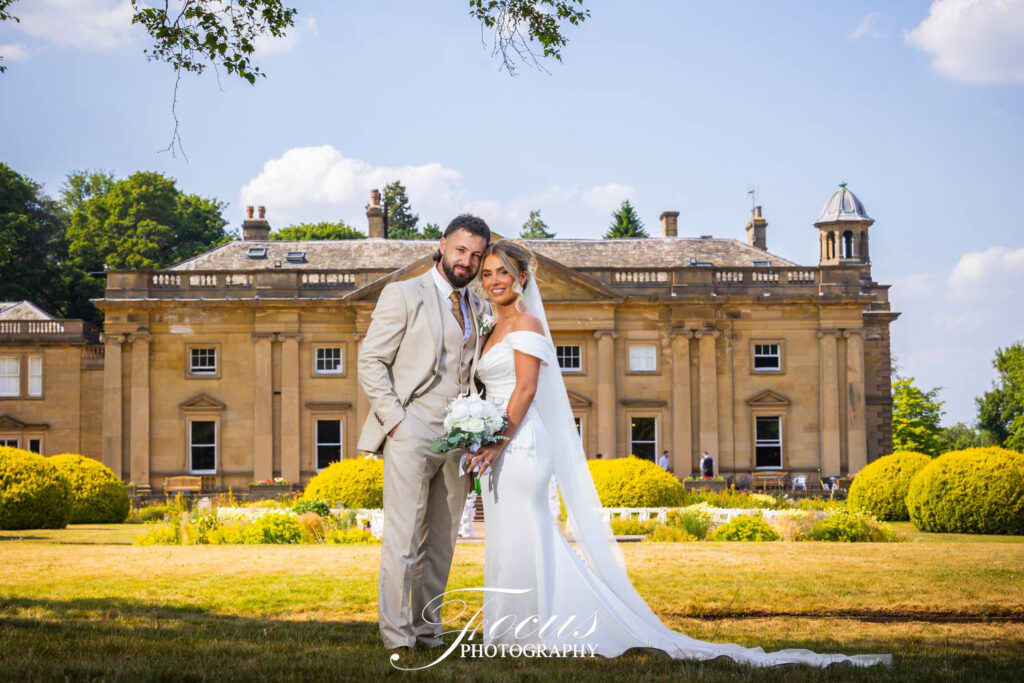 Bride and groom posing before grand country house